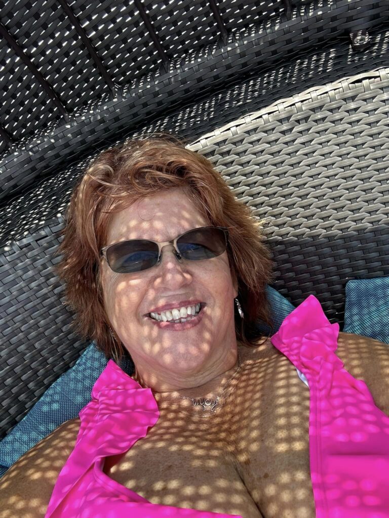 Smiling woman in sunglasses under wicker shade