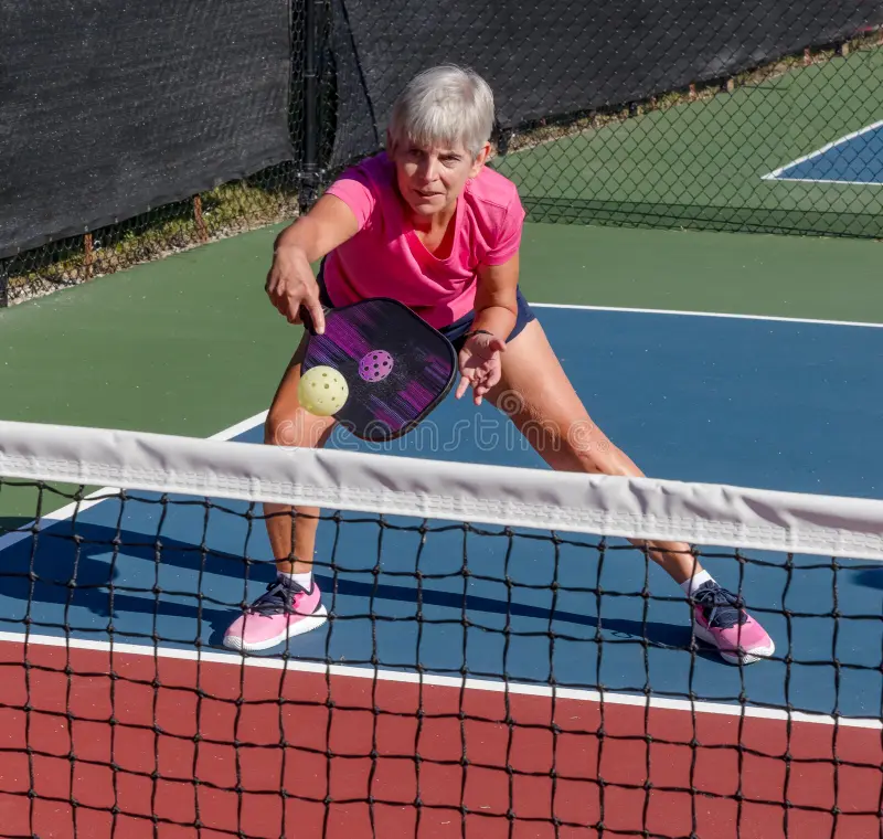 Woman playing pickleball on outdoor court