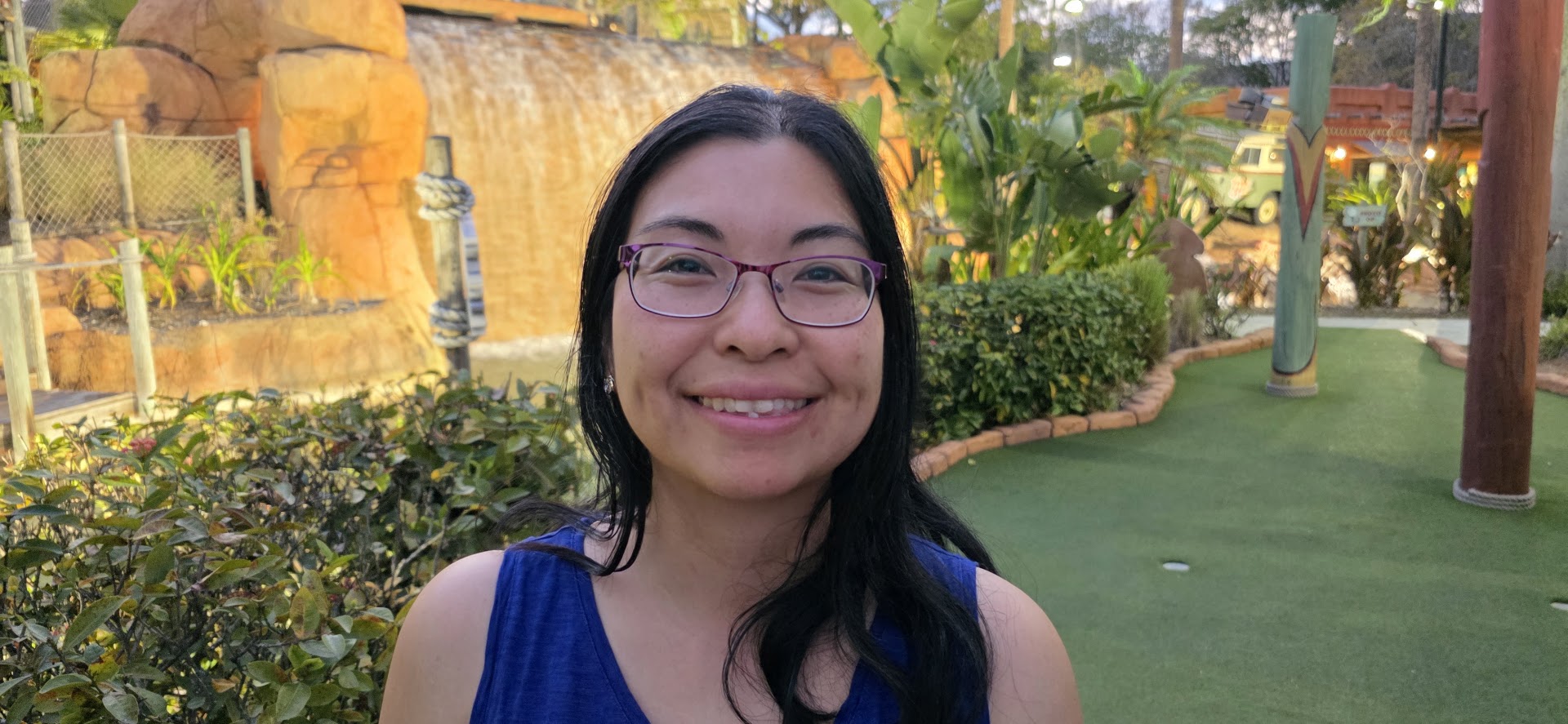 Smiling woman near waterfall and mini golf course